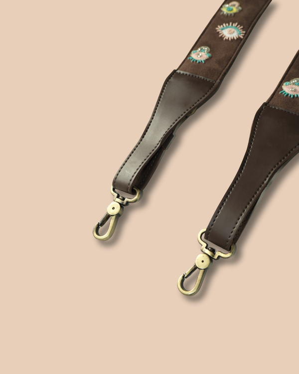 Brown leather strap with gold hardware on a beige background