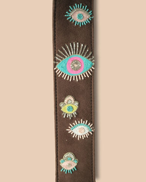 Decorative belt strap with eye-shaped designs on a beige background