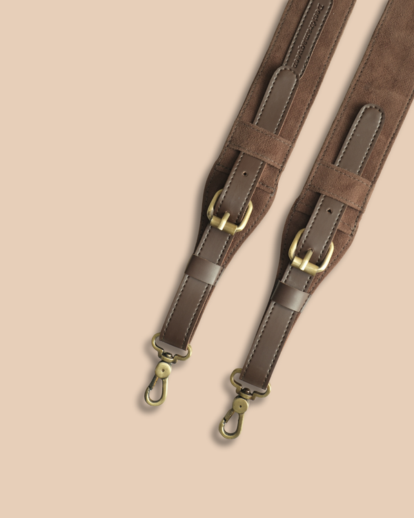 Brown leather strap with gold hardware on a beige background