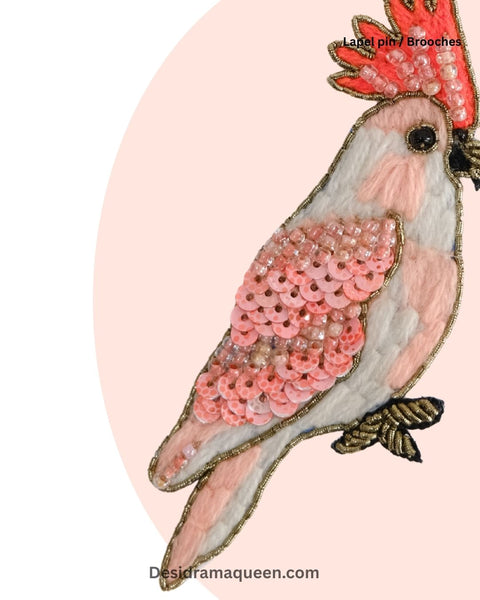 Handcrafted cockatoo bird brooch in pastel pink and coral with gold bead details, perfect statement accessory.