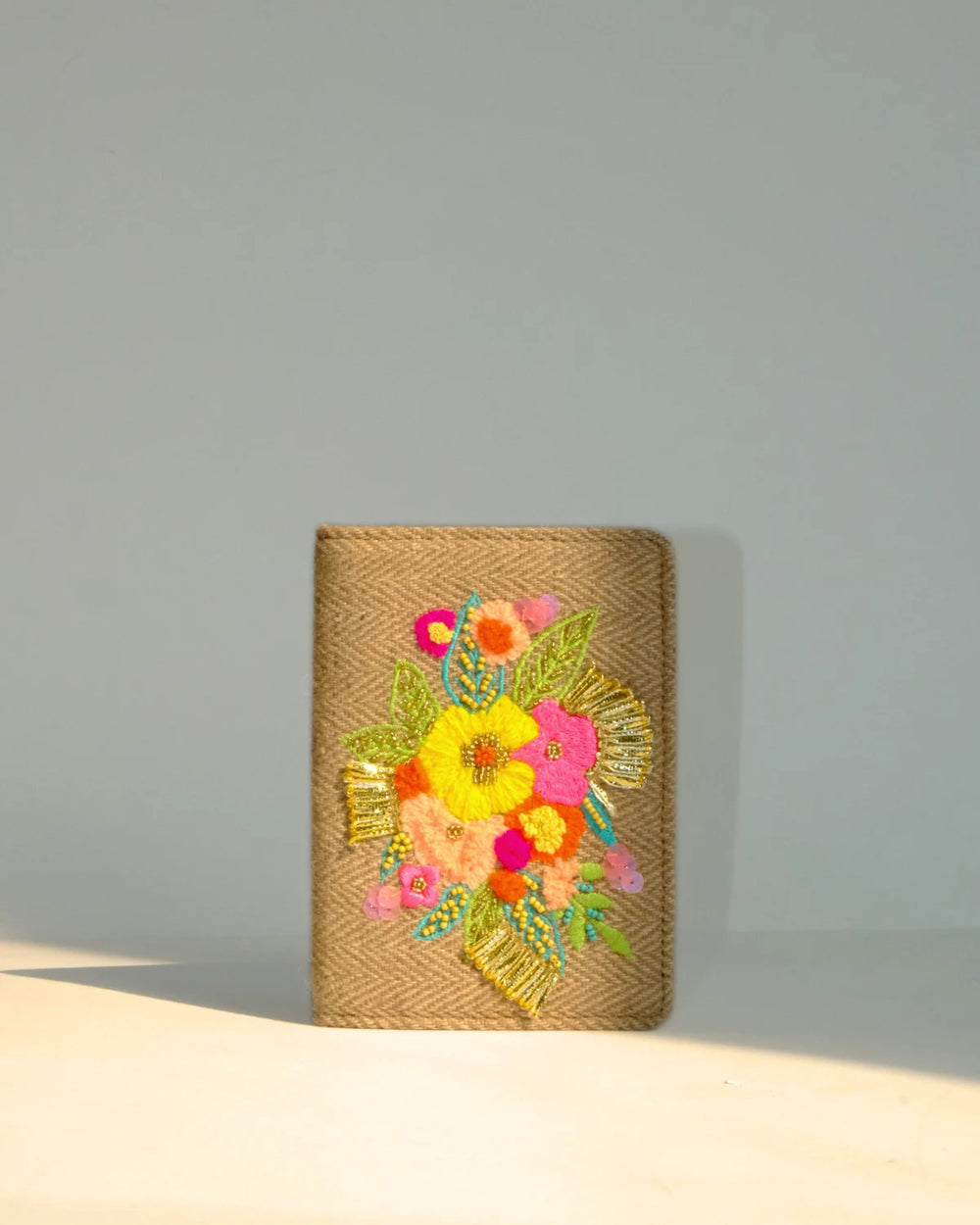 Woven clutch with colorful floral embroidery on a gray background