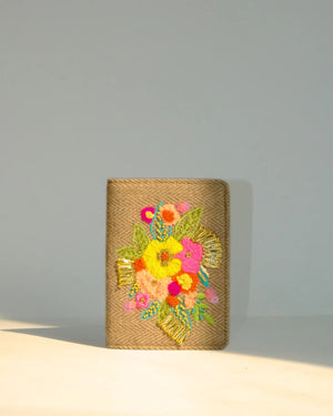 Woven clutch with colorful floral embroidery on a gray background