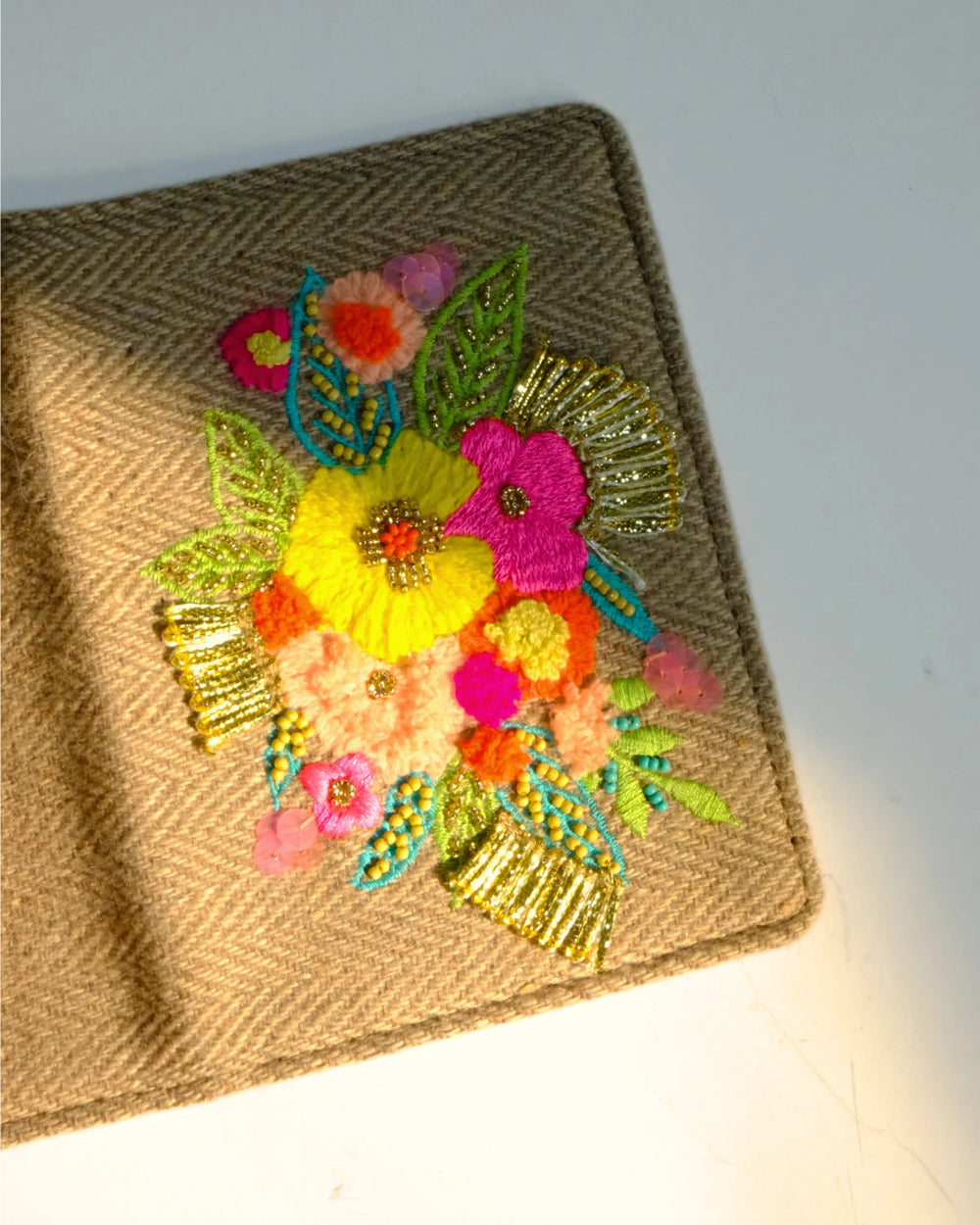 Woven clutch with colorful floral embroidery on a gray background