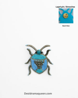 Handmade bug-inspired brooch with blue bead embroidery and metallic detailing, insect lapel pin.