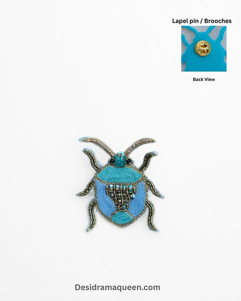 Handmade bug-inspired brooch with blue bead embroidery and metallic detailing, insect lapel pin.