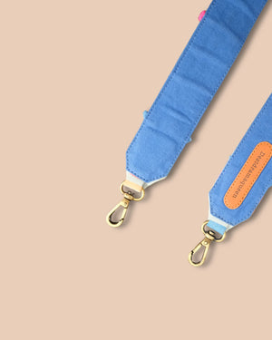 Blue bag strap with gold hardware on a beige background