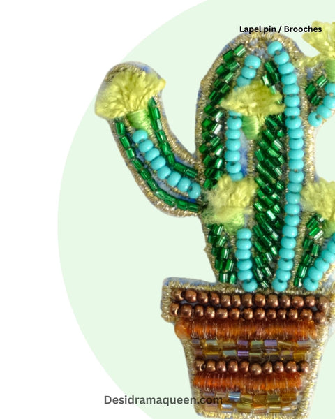 Colorful handmade cactus lapel pin featuring green beads, yellow thread accents, and a brown pot design.
