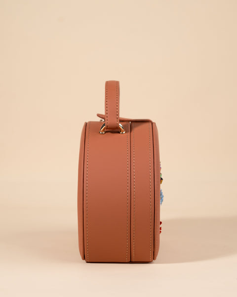 Stylish tan box sling featuring evil eye embroidery with traditional and modern craft elements