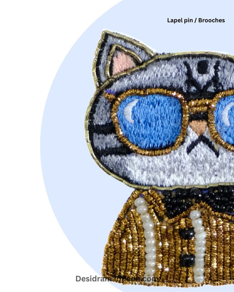 Stylish cat brooch with blue sunglasses and golden beaded tuxedo, handmade statement accessory for jackets, bags, and scarves.