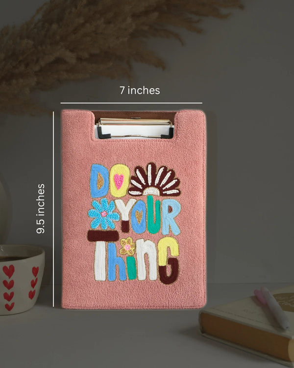 Pink clipboard with 'Do Your Thing' text and measurements on a dark background
