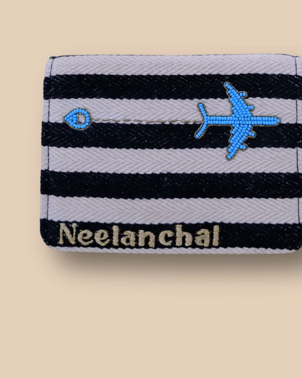 Black and white striped passport cover with embroidered blue airplane design.