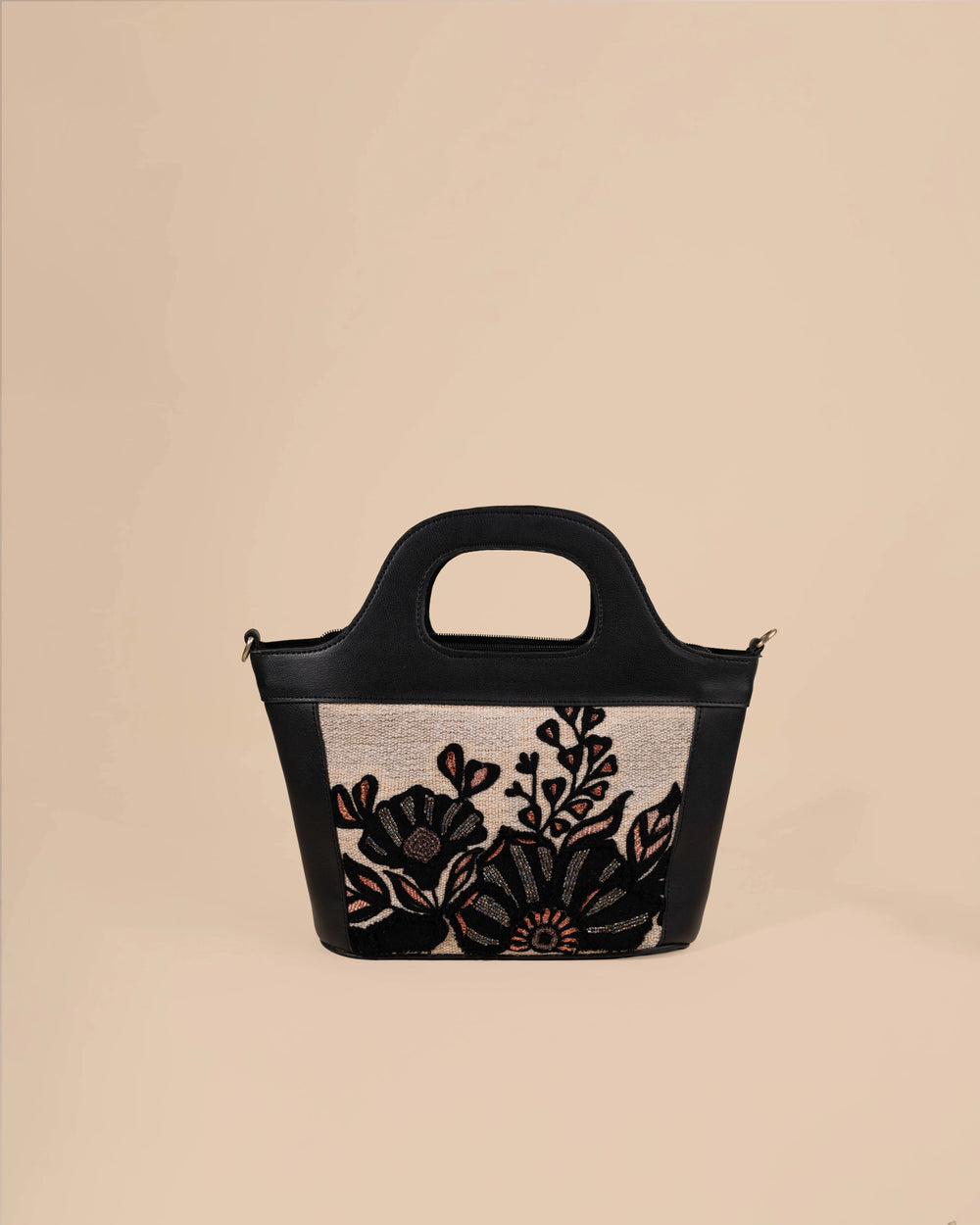 Black handbag with floral design on a beige background