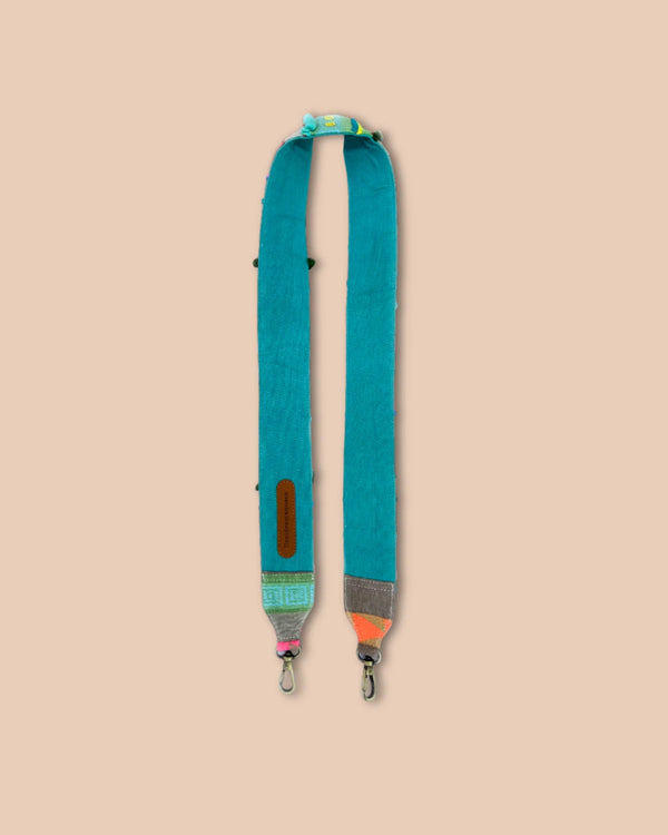 Teal bag strap with colorful accents on a beige background