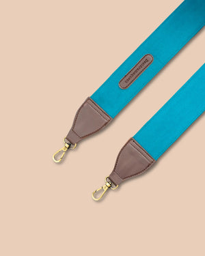 Blue strap with brown leather end and gold hardware on a beige background