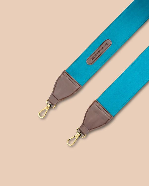 Blue strap with brown leather end and gold hardware on a beige background