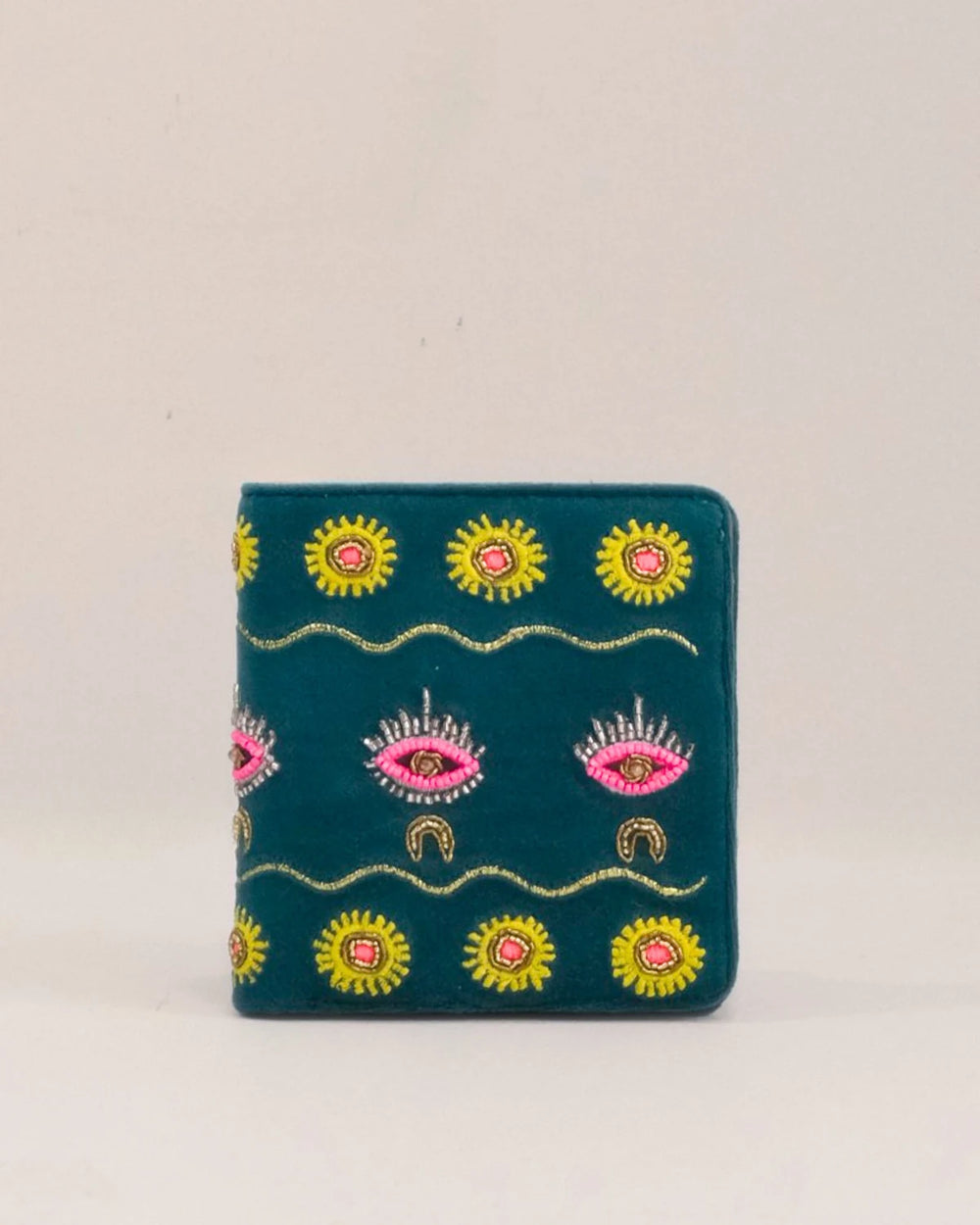 Embroidered wallet with sun and eye designs on a beige background