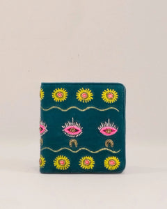 Embroidered wallet with sun and eye designs on a beige background
