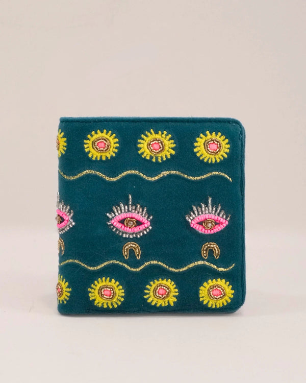 Embroidered wallet with eye and sun designs on a beige background