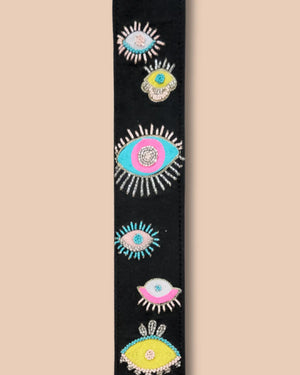 Decorative belt with colorful eye designs on a beige background