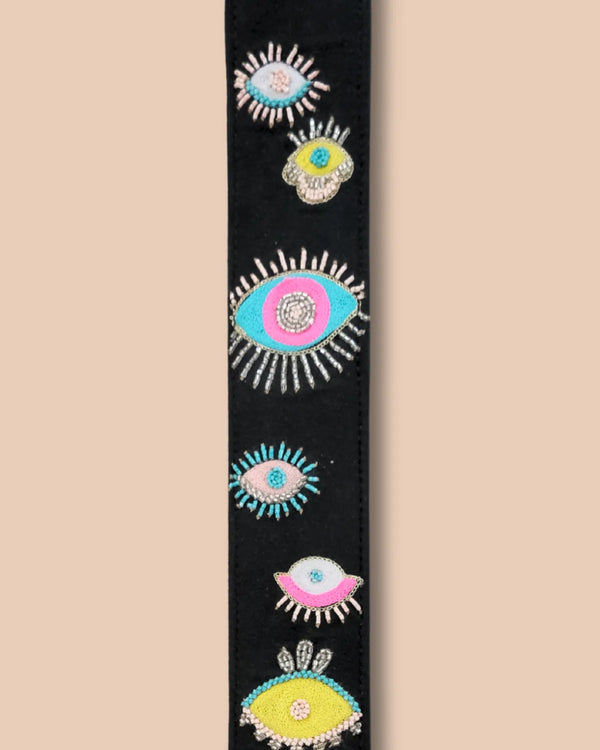 Decorative belt with colorful eye designs on a beige background
