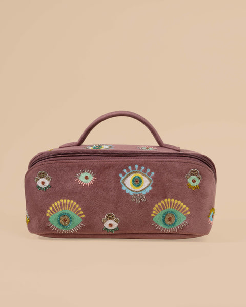 Dusty mauve makeup pouch with colorful evil eye embroidery, featuring zipper closure and top handle.