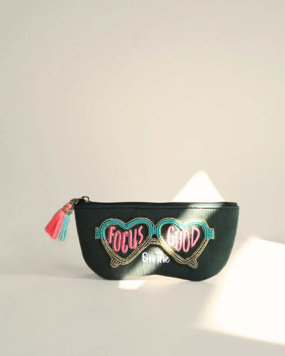 Black pouch with heart-shaped glasses design and 'Focus on Good' text on a light gray background
