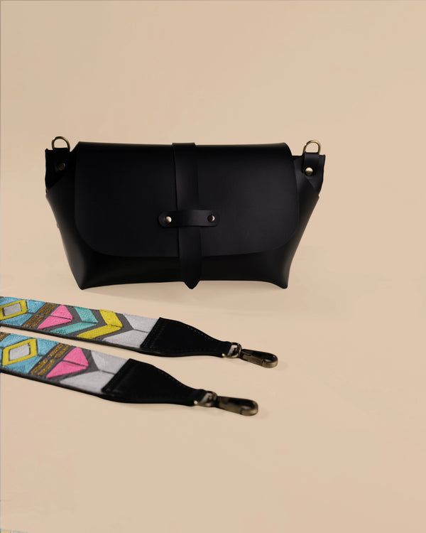Black leather bag with a colorful strap on a beige background