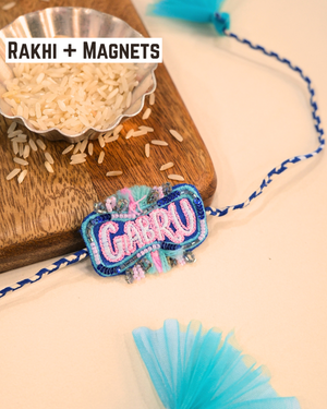 Gabru embroidered rakhi with glitter lettering placed beside a bowl of rice for a festive Raksha Bandhan celebration.