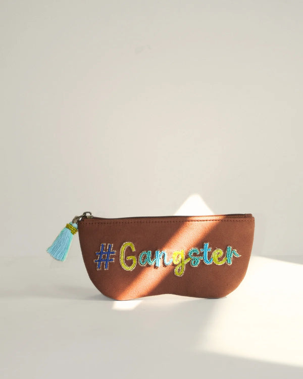 Brown pouch with '#Gangster' text and tassel on a light background