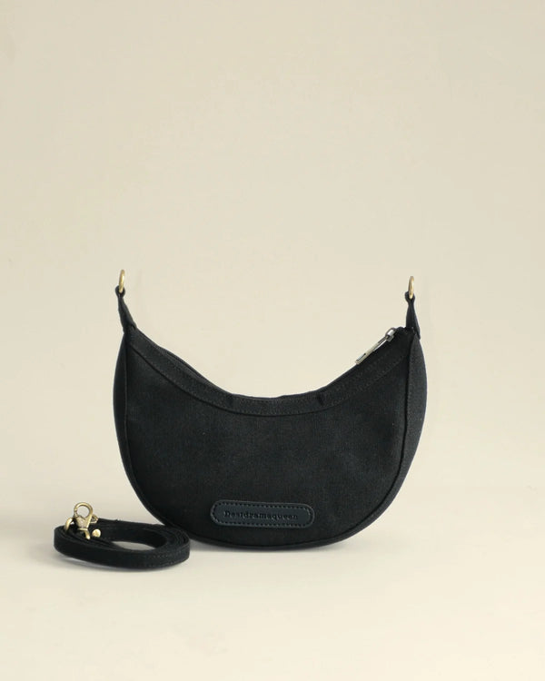 Black handbag with a strap on a beige background