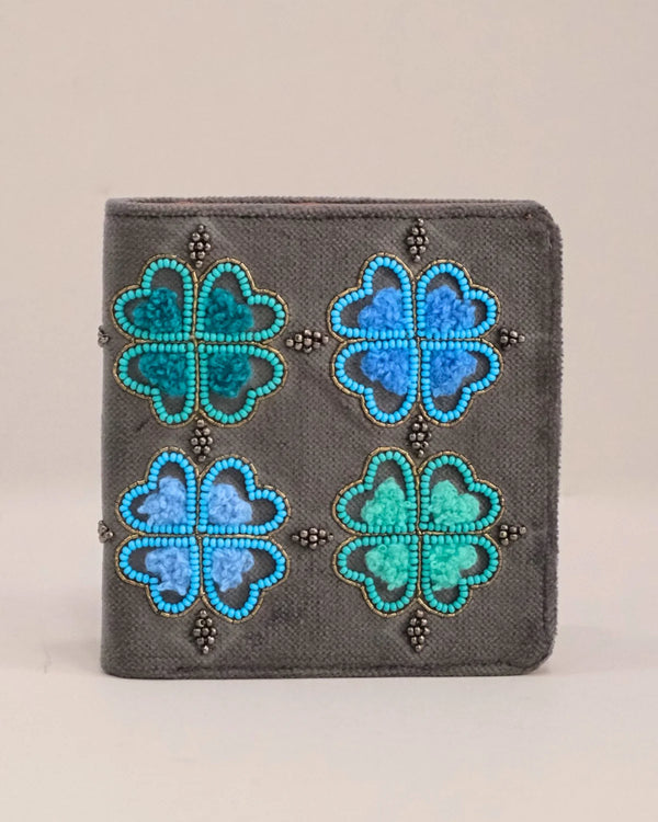 Gray wallet with blue and green floral patterns on a beige background
