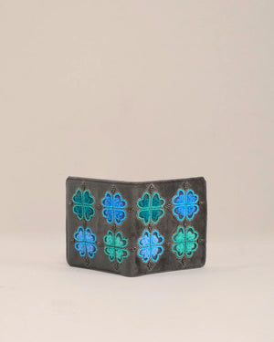 Small leather wallet with blue and green floral patterns on a beige background