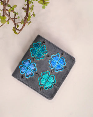 Gray wallet with blue and green floral patterns on a beige background