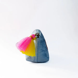 Small denim pouch with pink and yellow tassels on a white background