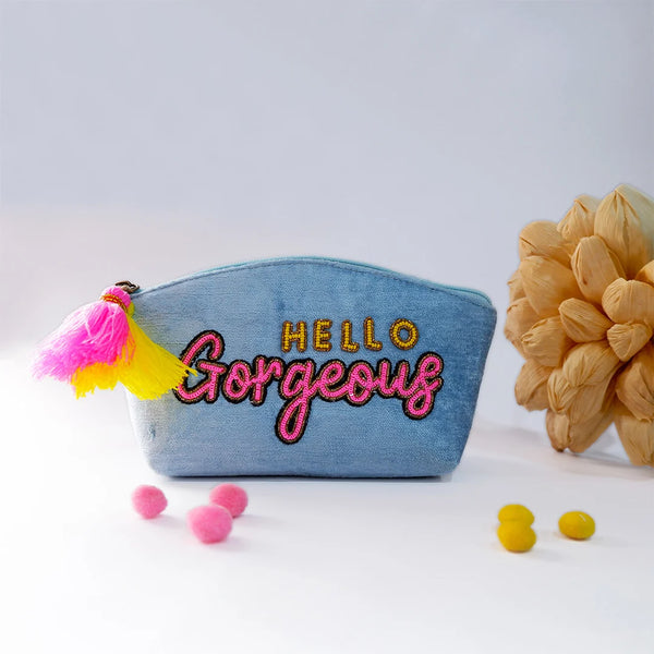 Denim pouch with 'Hello Gorgeous' text and tassels on a light background