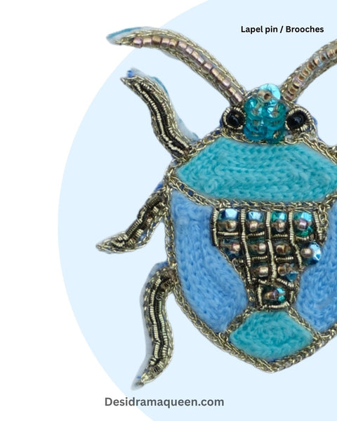 Unique handmade insect brooch with metallic and blue beadwork, perfect fashion accessory for jackets, bags, or scarves.
