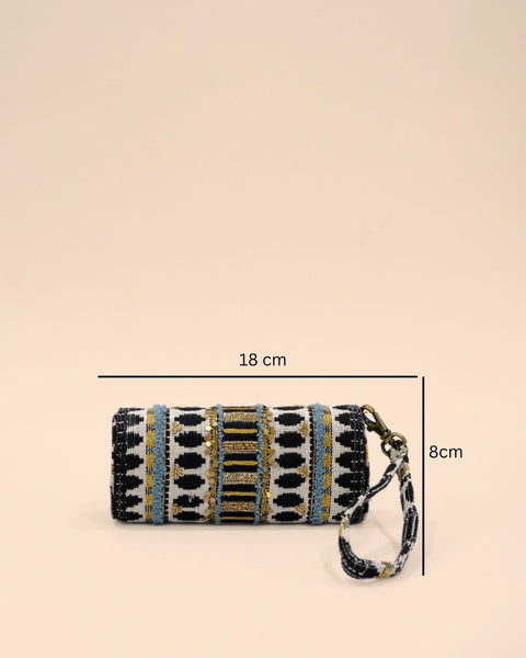 Cylindrical clutch with a wrist strap, decorated in black, white, gold, and blue tribal-inspired embroidery with sequins and intricate woven detailing