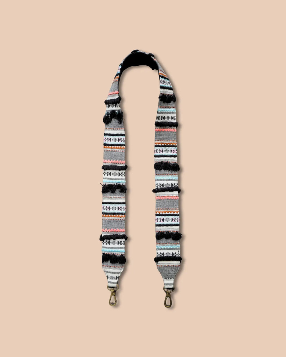 Patterned strap with gold hardware on a beige background
