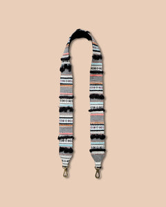 Patterned strap with gold hardware on a beige background