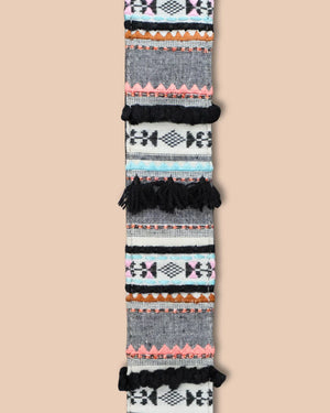 Woven belt with geometric pattern and black tassels on a beige background