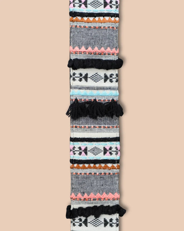 Woven belt with geometric pattern and black tassels on a beige background