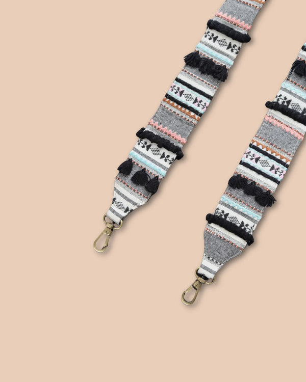 Patterned strap with pom-poms on a beige background