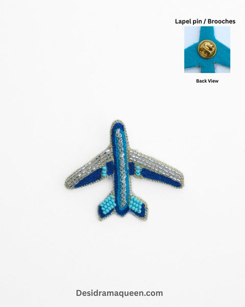 Handmade airplane brooch with silver, navy blue, and turquoise bead embroidery, travel-inspired lapel pin for jackets and bags.