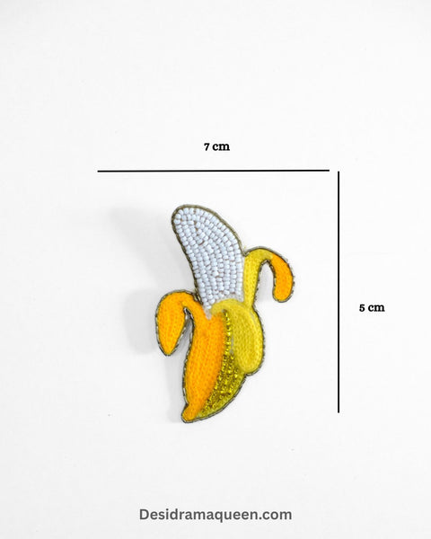 Quirky banana brooch with yellow bead embroidery and green leaf detail, handmade fruit lapel pin for jackets and bags