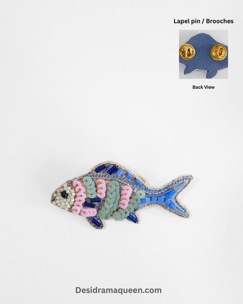 "Handmade beaded fish brooch with blue body, pink and green sequins, and ivory bead details, ocean-inspired lapel pin.