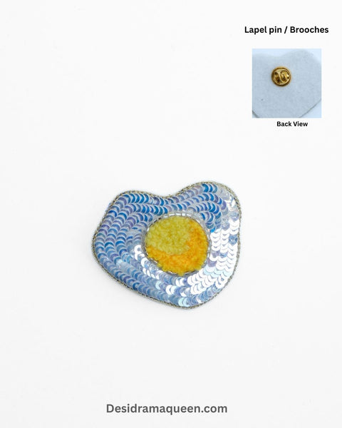Handmade fried egg brooch with sequins and bead embroidery, designed as a sunny-side-up egg.