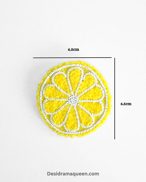 Bright yellow lemon brooch with green leaf detail, handmade with beads and embroidery for quirky fashion accessories