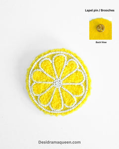 Yellow embroidered lemon slice brooch with white bead detailing, quirky handmade fruit accessory for jackets and bags.