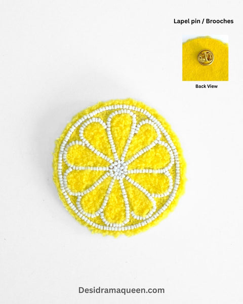 Yellow embroidered lemon slice brooch with white bead detailing, quirky handmade fruit accessory for jackets and bags.