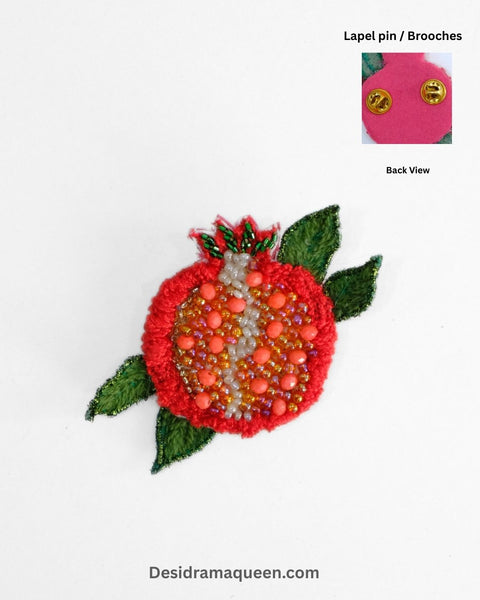 Handmade embroidered pomegranate brooch with red beadwork, green leaves, and gold accents, fruit lapel pin for jackets and bags.